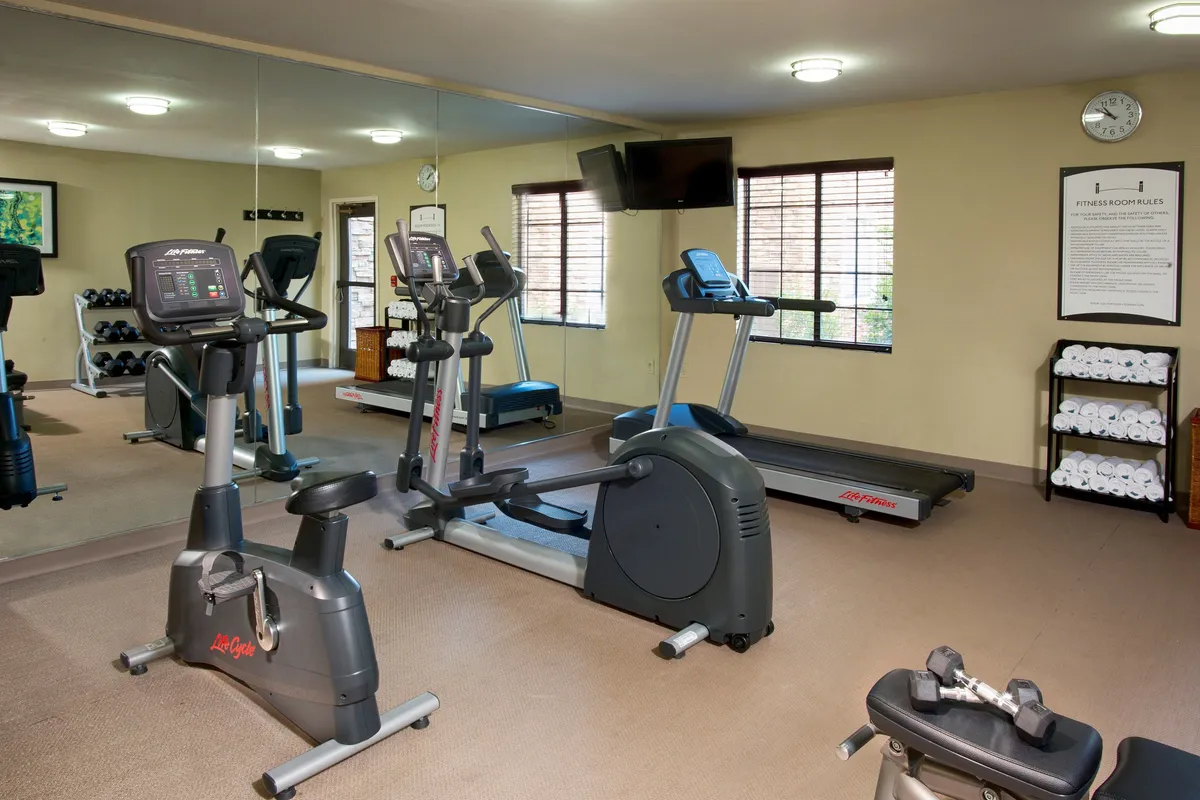 The interior gym is equipped with modern treadmills, stationary bikes, and a variety of workout equipment, set in a bright, motivational environment ideal for business travelers looking to unwind or stay active.