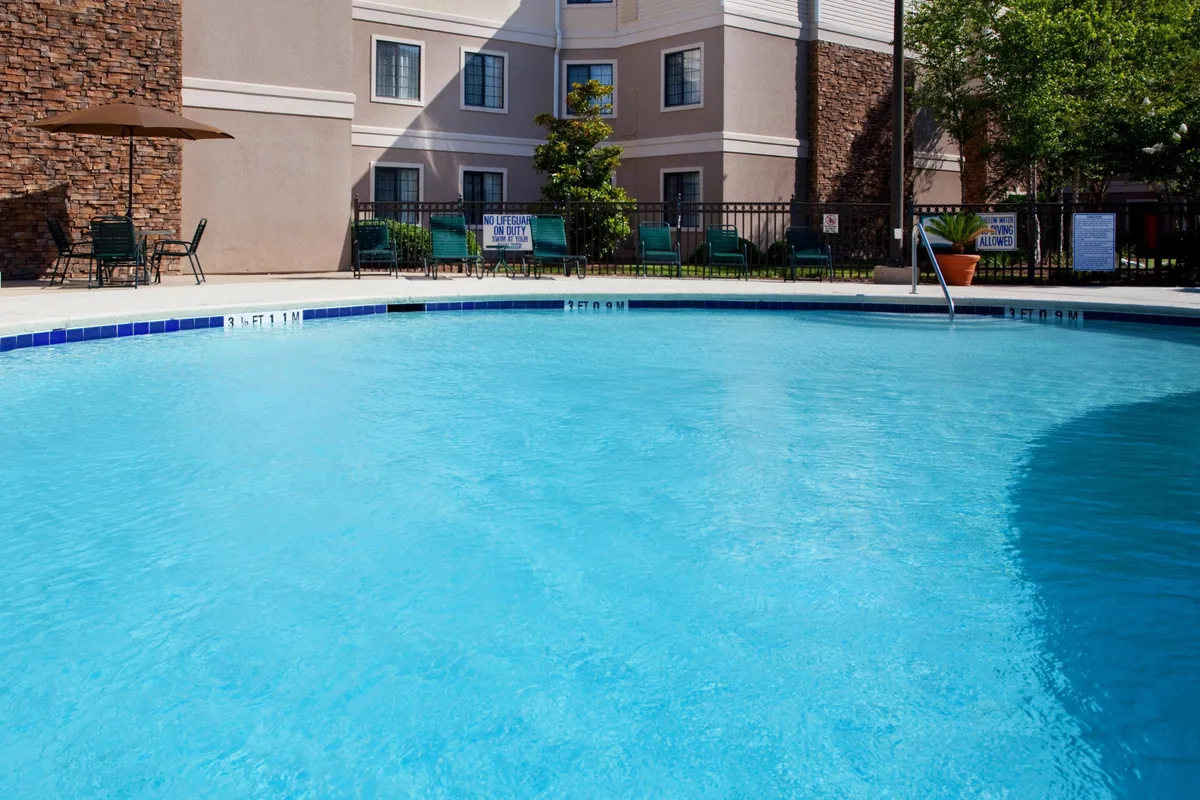 A serene shot of the property's outdoor swimming pool at sunset, flanked by rows of lounge chairs and umbrellas. The inviting pool area sits in front of the building facade, radiating a relaxed and welcoming atmosphere perfect for unwinding after a day exploring Myrtle Beach.