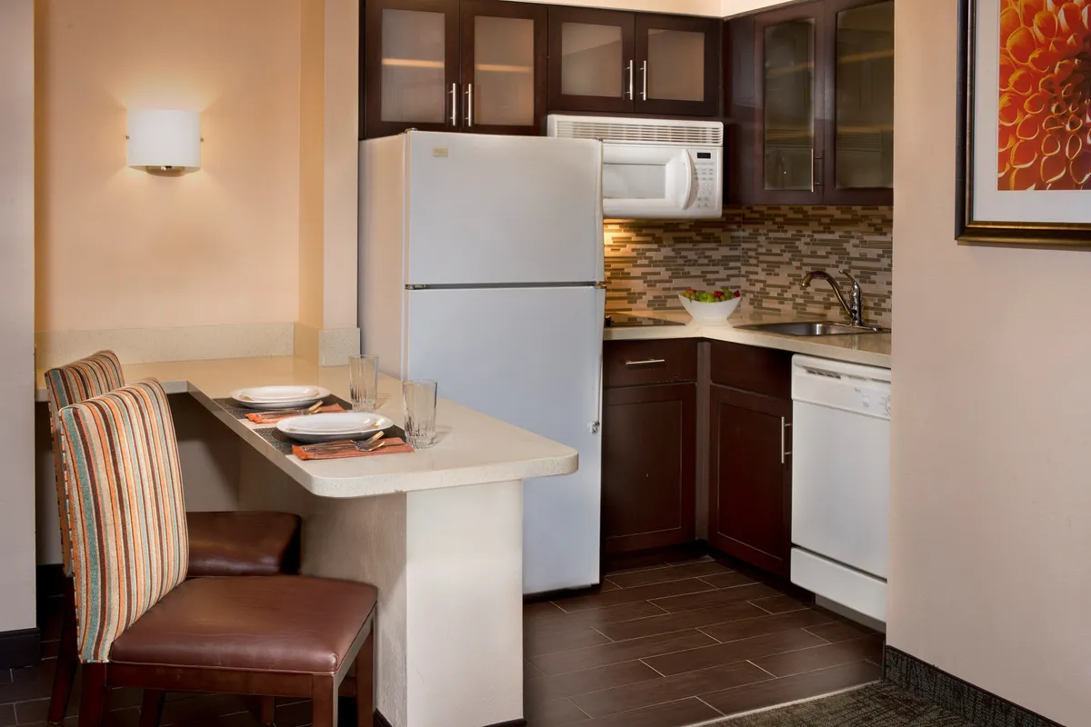 A welcoming kitchen and dining area featuring a full-size refrigerator, built-in dishwasher, expansive countertop, and view of a cozy dining space. Modern appliances and ample seating make the area ideal for preparing meals and connecting with others.